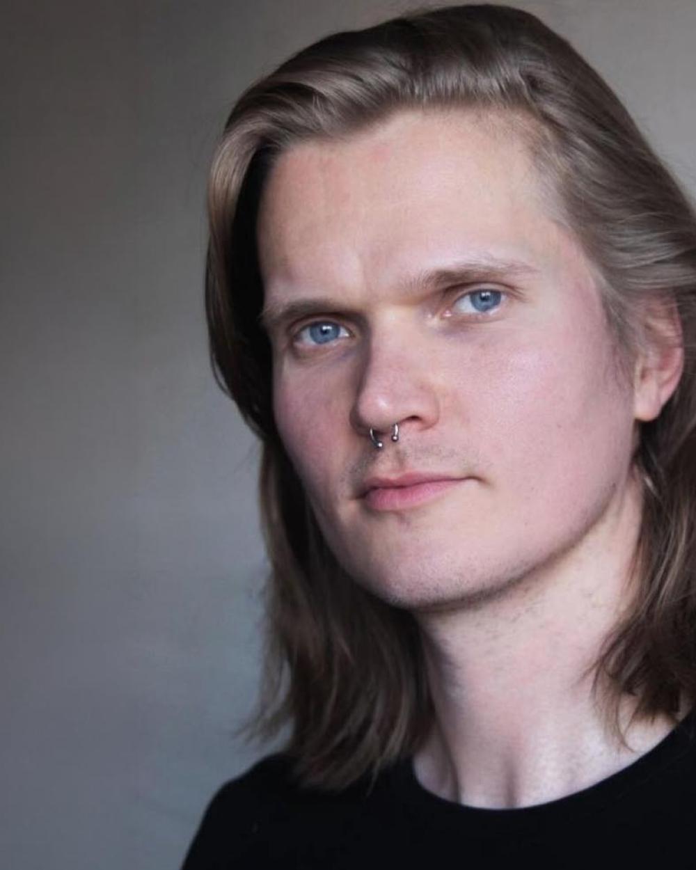 Danskonstnären Johannes Purovaara med axellångt ljust hår och en svart tröja.