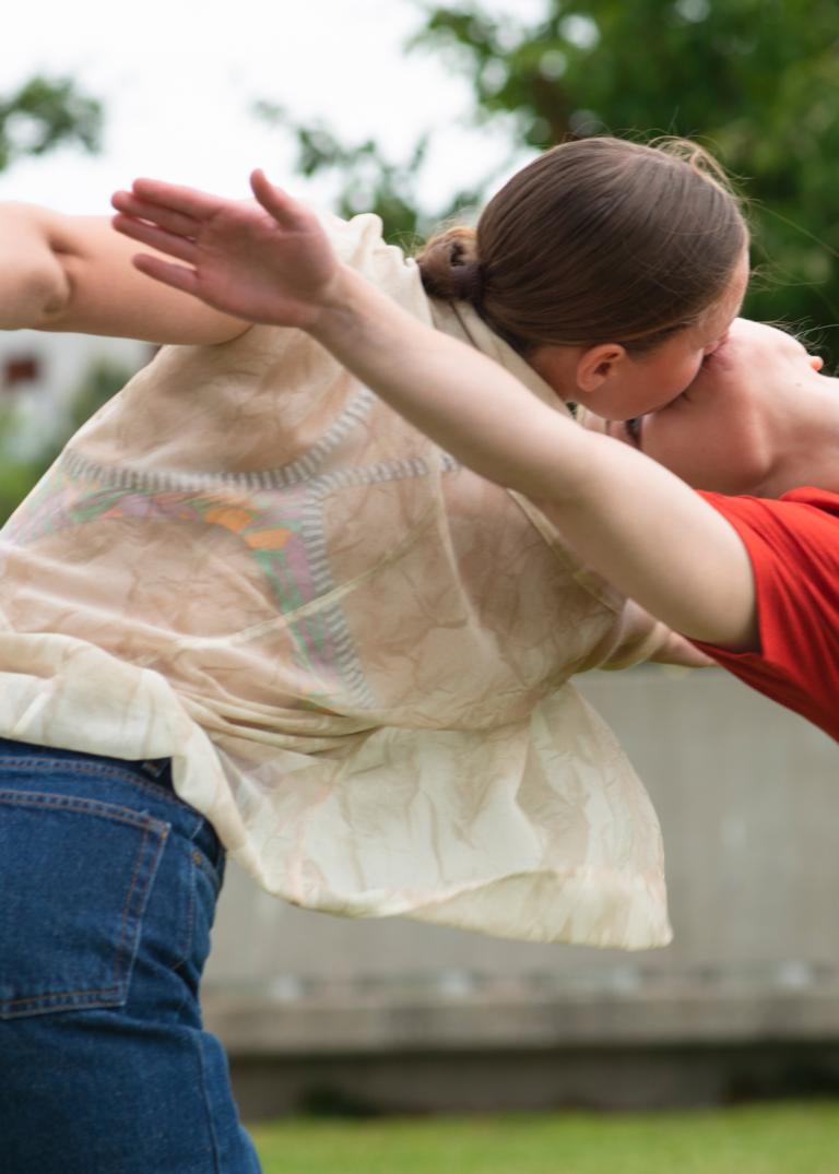 Dansarna Jeanne och Emma dansar mun mot mun men vända med kropparna bort från varandra och armarna utsträckta.
