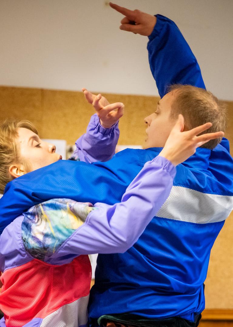 Två dansare står med armarna om varandra och gestikulerar ivrigt. Ur Regionteater Blekinge Kronobergs dansföreställning Sch!