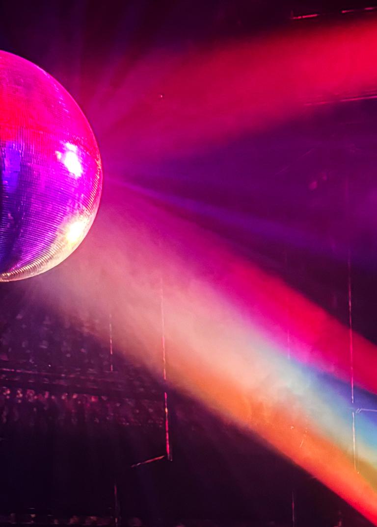 Strålkastarljus i rött, blått, grönt och gult lyser på en discoboll.