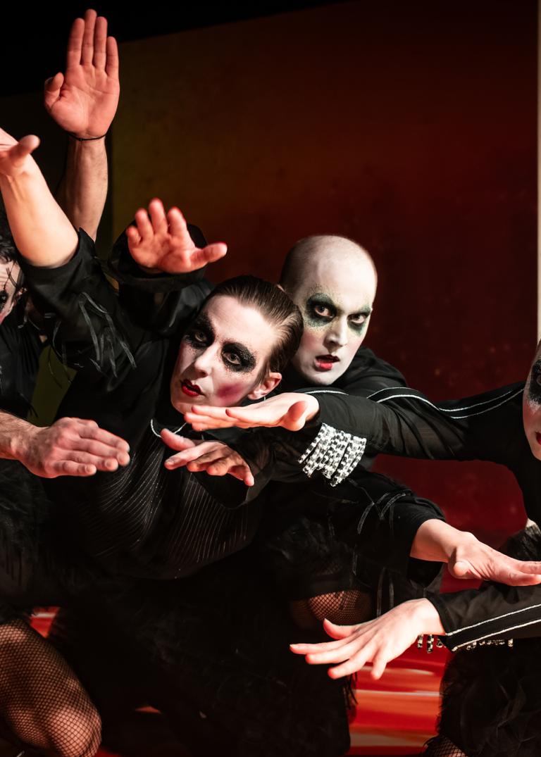 Fyra dansare hukar tillsammans med sina armar utsträckta som vingar. 