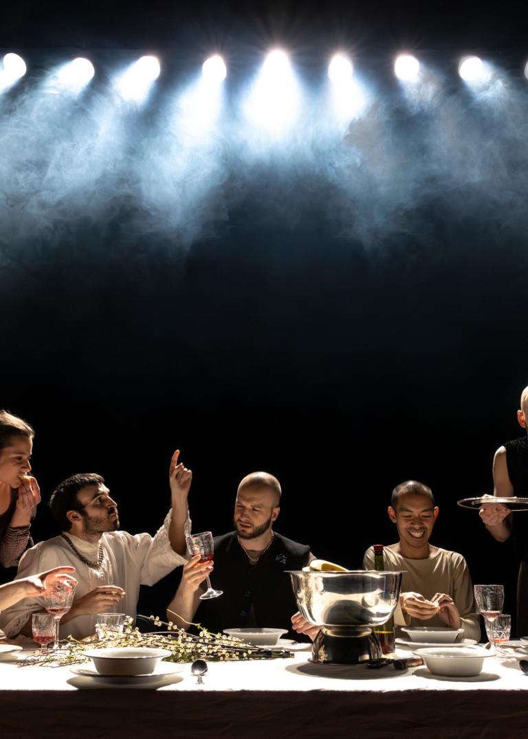 Skånes Dansteaters dansare sitter vid ettlångt bord dukat för fest. De äter, pratar, skrattar och dricker.