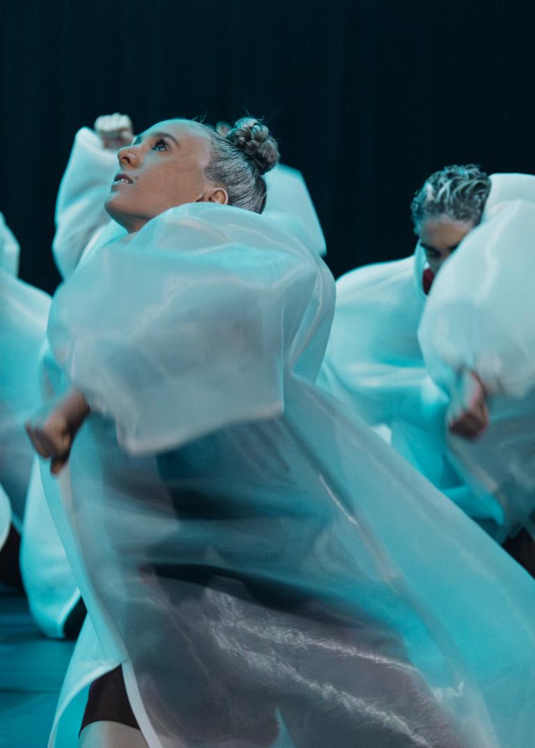 Dansare klädda i vita puffiga rockar dansar i blåskimrande ljus i dansföreställningen Invisible Rulers.