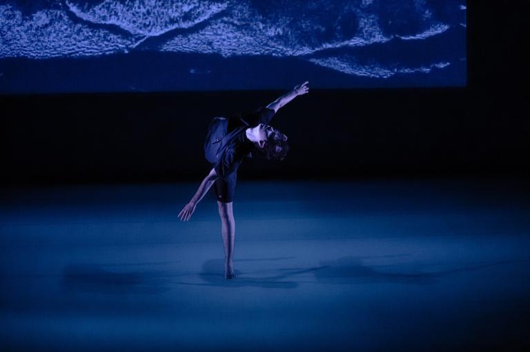 En dansare står på ett ben med armarna och sitt andra ben utsträckta från kroppen.