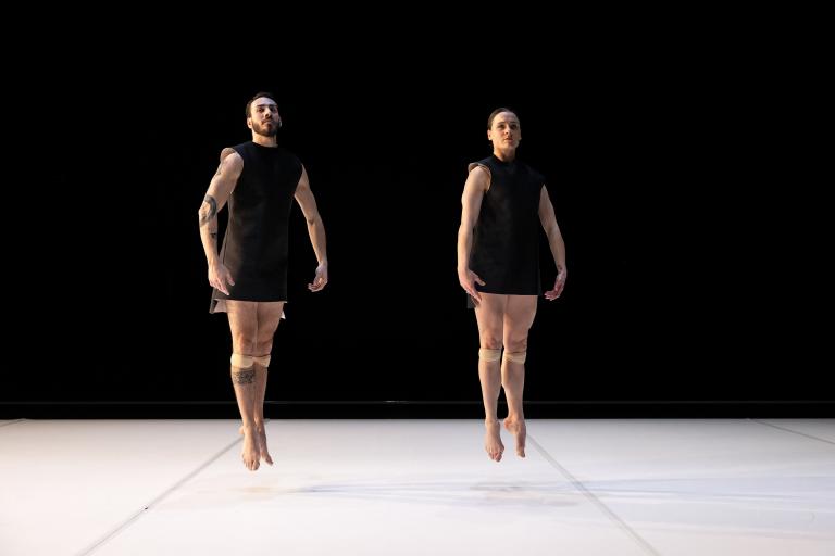 Dansarna Simone Frederick Scacchetti och Amy Josh i korta svarta tunikor gör baletthoppet soubresaut.