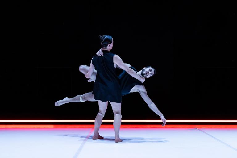 Dansaren Amy Josh bär dansaren Simone Frederick Scacchetti i en axel och ett ben. 