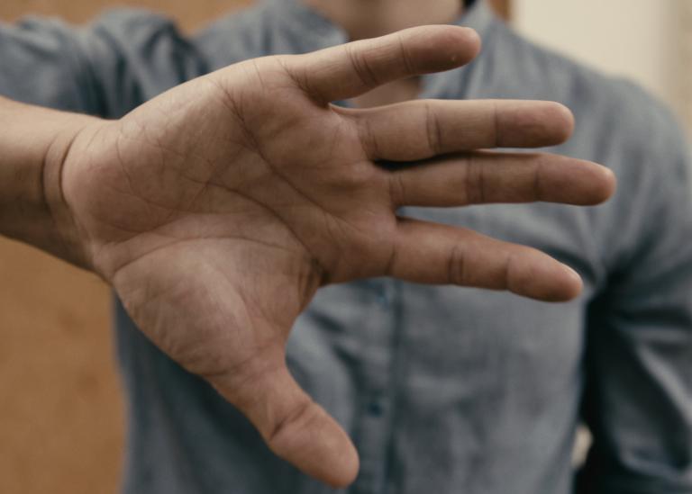 En dansare i blå skjorta håller fram sin öppna hand mot dig. 