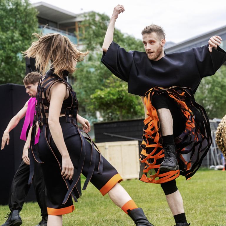 Dansare i kontrastrika kläder dansre mot varandra. 