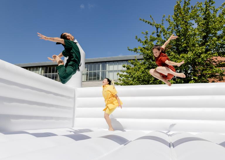 Skånes Dansteaters dansare Michael Kit Brown, Hazuki Kojima och Marion Rastouil i flygande hopp i en vit hoppborg i dansföreställningen UP-AND-DOWN-AND-UP- av koreografen Jernej Bizjak.