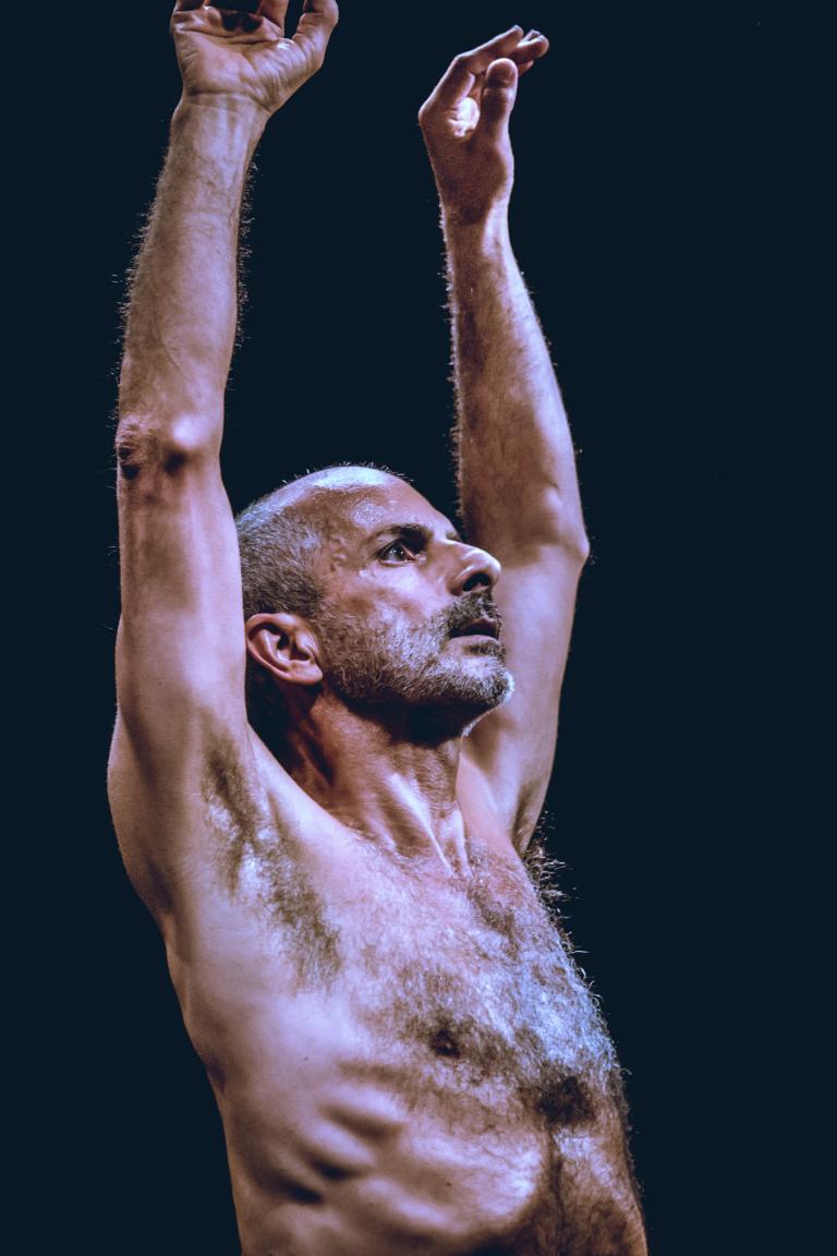 Dansaren Amancio utan tröja och sträcker sina armar upp i luften. En del av dansföreställningen The Still Dying Swan.