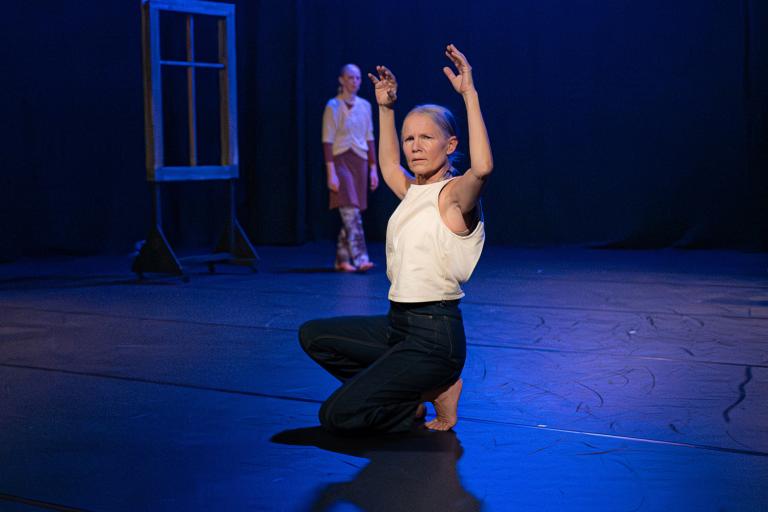 Dansaren och koreografen Helena Franzen sitter med ett knä mot golvet och sträckar upp armarna strax över huvudet i dansföreställningen Inner Song. 