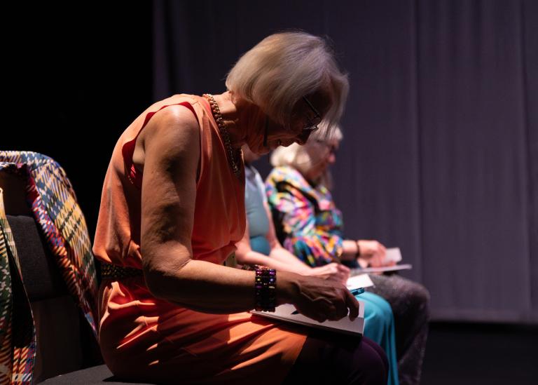 Gästdansare över 60 år sitter på stolar på rad och antecknar i anteckningsböcker i dansföreställningen Jag minns mig själv.