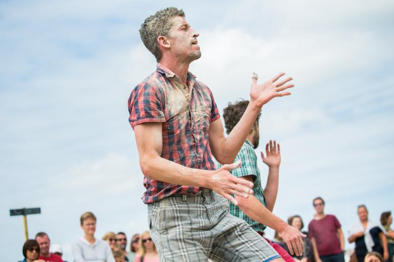 En dansare i rutig skjorta med ansiktet och skjortan täckt av damm dansar.