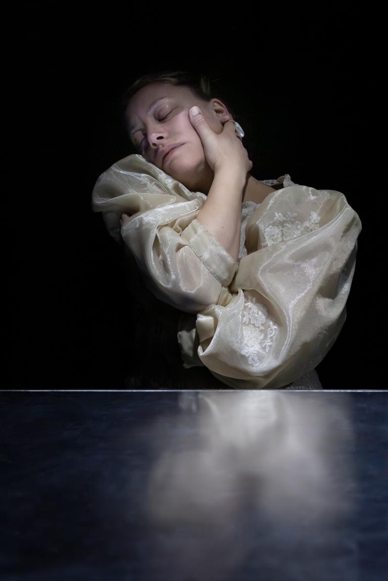 Dansaren Madeleine klädd i cremefärgad puffig blus blundar avslappnat och kramar om sig själv.