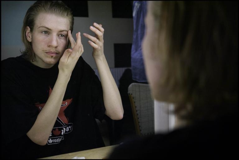 En person sminkar sig framför en spegel.