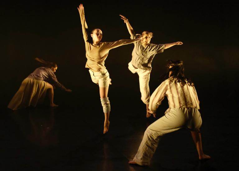 Två danselever från Malmö Kulturskola gör ett stort danssprång mellan två dansare.