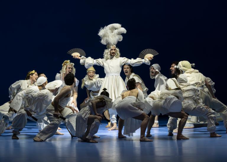 Skånes Dansteaters dansare klädda i olika vita kläder med historiska detaljer dansar runt dansaren Kit Brown som står i mitten med blond lockig peruk och strutsfjädrar på huvudet i Skånes Dansteaters dansföreställning Out of the Blue.