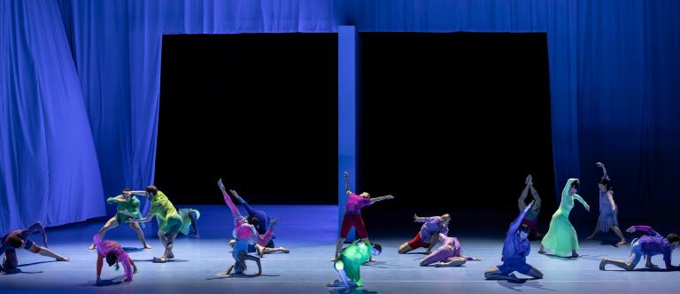 Dansare i tunna kläder i klara färger dansare på scen bland fladdrande blå skynken i Skånes Dansteaters dansföreställning Out of the Blue.