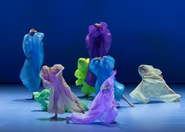 Dansare täckta i skira overaller i klara färger dansar i Skånes Dansteaters dansföreställning Out of the Blue.