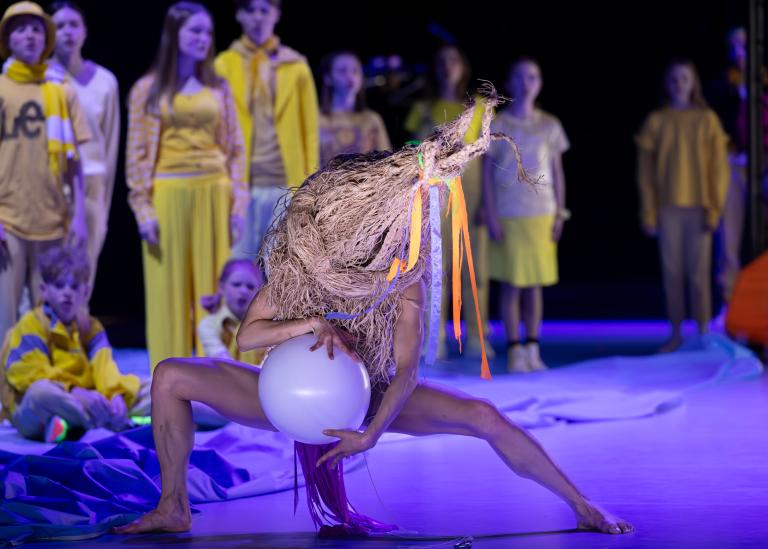 En dansare dansar med en vit ballong klädd i en stor halmhatt som täcker halva kroppen i Skånes Dansteaters dansföreställning Out of the Blue.