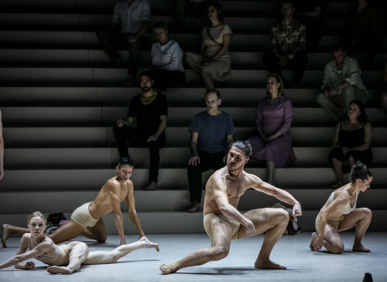 Dansare i hudfärgade underkläder dansar med armar och ben sträckta i olika vinklar.