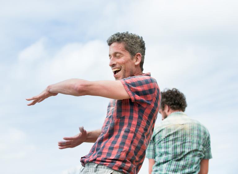 En dansare i rutig skjorta skrattar och slår sig för magen. 