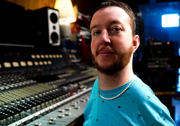 Kompositören och musikern Tim Palm med rött kort skägg och turkos tröja i ljudstudion.
