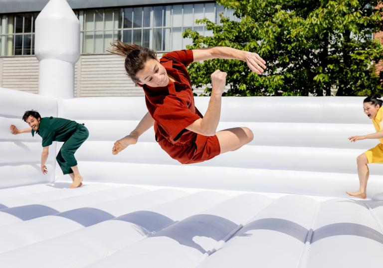 Skånes Dansteaters dansare Marion klädd i röda shorts och skjorta vänder sig i en studs i en vit hoppborg i oreografen Jernej Bizjaks dansföreställning Up-And-Down-And-Up-.