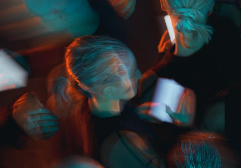 Dansaren Pili lyfter sitt ansikte från sin mobilskärm och ser på dig