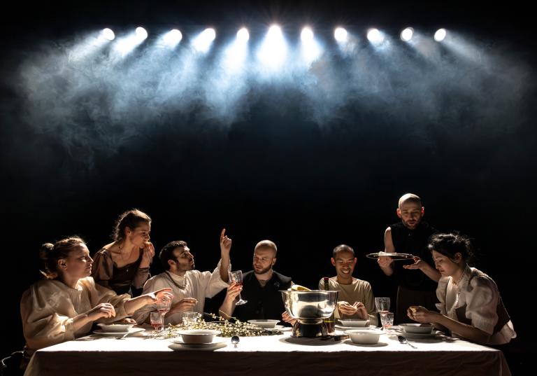 Skånes Dansteaters dansare sitter vid ettlångt bord dukat för fest. De äter, pratar, skrattar och dricker.