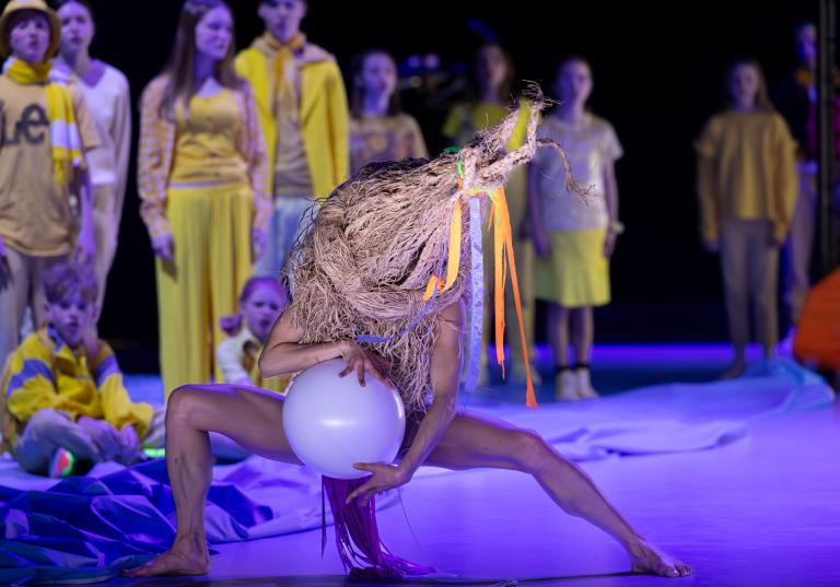 En dansare dansar med en vit ballong klädd i en stor halmhatt som täcker halva kroppen i Skånes Dansteaters dansföreställning Out of the Blue.