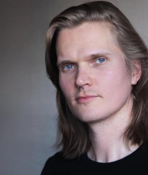 Danskonstnären Johannes Purovaara med axellångt ljust hår och en svart tröja.