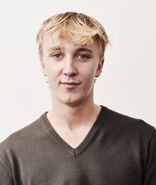 Dansaren Oliver Lund klädd i olivgrön v-ringad tröja. Han har ljust kortklippt hår med en yvig lugg.